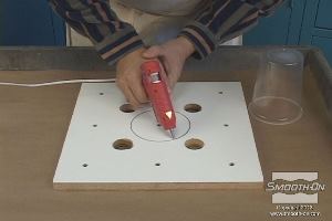 לחיצה להגדלת תמונה מדביקים את מיכל הפלסטיק למרכז לוח הבסיס בעזרת דבק חם.