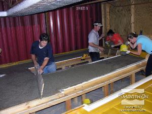 לחיצה להגדלת תמונה מפזרים את הבטון באופן אחיד בתבנית בעזרת לוחות עץ.