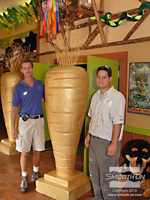 לחיצה להגדלת תמונה ריצ'ארד בוטורלה (שמאל) ופיטר ירקה (ימין) עומדים ליד פיסול קלקר מצופה Styrocoat של גזר זהב ענק - דוגמה נוספת למה שניתן להשיג בשימוש בפלסטיק לציפוי קצץ פוליסטירן Styrocoat.