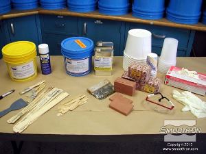 לחיצה להגדלת תמונה ביום שאחרי מכינים את מעיל התמיכה. ראשית מסדרים את כל החומרים והכלים עבור התהליך: פוליאוריתן קשיח למריחה מחוזק בסיבים Plasti-Paste, חומר אטימה Sonite® Wax, חומר הפרדה Universal® Mold Release וחימר LBT ללא גופרית. כוסות מדידה, כפפות, משקפי מגן, שפכטל ממתכת 