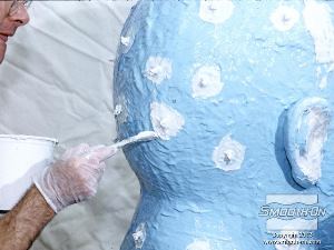 לחיצה להגדלת תמונה שמים על המודל חתיכות חבל קטנות ומכסים אותן בגומי, כדי ליצור מתפחות נעילה שיעזרו למקם את מעיל התמיכה והתבנית הגמורה.