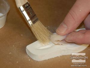 לחיצה להגדלת תמונה משתמשים במברשת כדי לחלוץ את יציקת הסיליקון מ תבנית פוליאוריטן Smooth Cast 300.