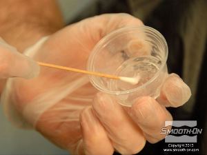 לחיצה להגדלת תמונה אוספים כמות קטנה של דבק סיליקון Skin Tite בעזרת מקל אוזניים.