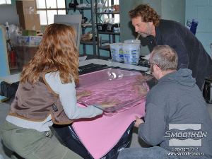 לחיצה להגדלת תמונה דרושים לפחות 3 אנשים כדי לחלוץ את לוח הפלסטיק השביר. מרימים את הלוח הSMASH פוליאוריטן דמוי הזכוכית ותבנית הסיליקון נופלת ממנו.