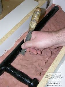 לחיצה להגדלת תמונה שמים את מודל אלת המשטרה בתוך המסגרת. מכסים את המודל המקורי עד בחימר עד שחצי ממנו מכוסה וחצי חשוף- למעשה מכינים קו חלוקה.