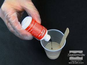 לחיצה להגדלת תמונה מעבירים את המנה השניה של מקשה הפוליאוריתן ליציקה Smooth-Cast® 60D למיכל ערבוב גדול יותר ומוסיפים לו מספר טיפות פיגמנט So-Strong כתום.