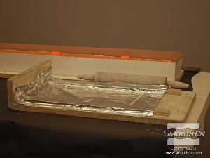 לחיצה להגדלת תמונה משתמשים בלוח לחימר מכוסה בנייר אלומיניום ומארוך, כדי לרדד את האפוקסי לעובי אחיד.